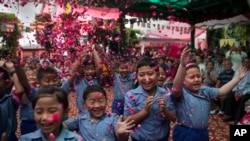 Anak-anak sekolah di pengasingan menebarkan bunga sambil menyanyikan lagu selamat ulang tahun bagi Dalai Lama di New Delhi, India (6/7).