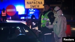슬로베니아 방역 당국 관계자가 지난해 3월 이탈리아 국경에서 차량 여행자를 점검하고 있다. 