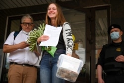 FILE - Russian journalist Svetlana Prokopyeva smiles while holding flowers after a court session in Pskov, Russia, July 6, 2020. A court in Pskov convicted Prokopyeva on charges of condoning terrorism.