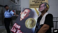 A pro-democracy protester wears a mask and holds a picture of Chinese dissident Liu Xiaobo while demanding Liu's release outside China's Liaison Office in Hong Kong, 11 Oct 2010