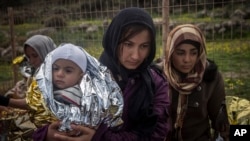 FILE - Women and children stand on a road after their arrival on a dinghy with other refugees and migrants from the Turkish coast to the Greek island of Lesbos, on Wednesday, Nov. 25, 2015.