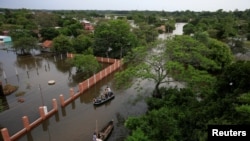 La gente viaja en botes en un área inundada después de que el río Paraná se desbordó debido a las fuertes lluvias, en Ayolas, Paraguay, 8 de noviembre de 2023.