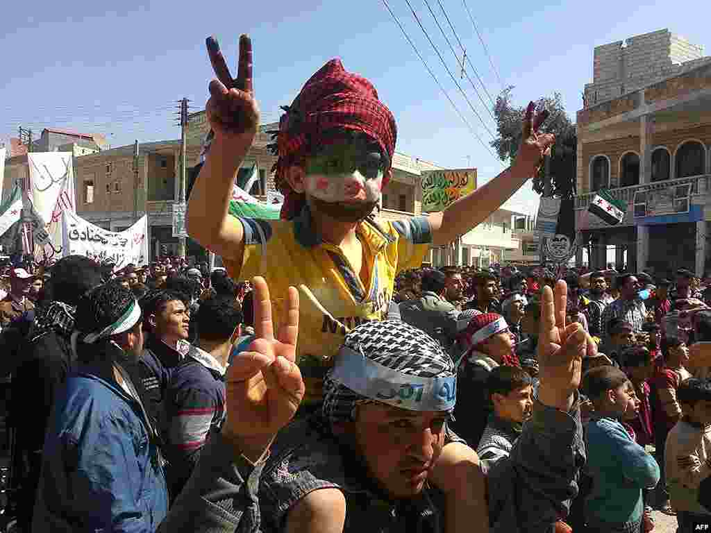 This citizen journalism image taken shows an anti-Syrian regime protester carrying a boy with the Syrian revolution flag painted on his face, Binish, Idlib. (A/Edlib News Network) 