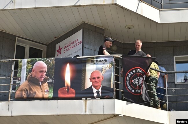 A view shows a banner with portraits of Russian mercenary chief Yevgeny Prigozhin and Wagner group commander Dmitry Utkin at a makeshift memorial outside the local office of the Wagner private mercenary group in Novosibirsk, Russia August 24, 2023. (REUTERS/Stringer)