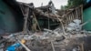 FILE - Members of the Mandalay Peoples Defense Forces (MDY-PDF) walk through a structure bombed by a Myanmar military aircraft near the front line amid clashes in northern Shan State, Dec. 11, 2023.