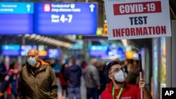 A man holds a sign leading the way to a Covid-19 test center the airport in Frankfurt, Germany, Oct. 22, 2020.