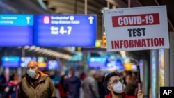 A man holds a sign leading the way to a Covid-19 test center the airport in Frankfurt, Germany, Oct. 22, 2020.