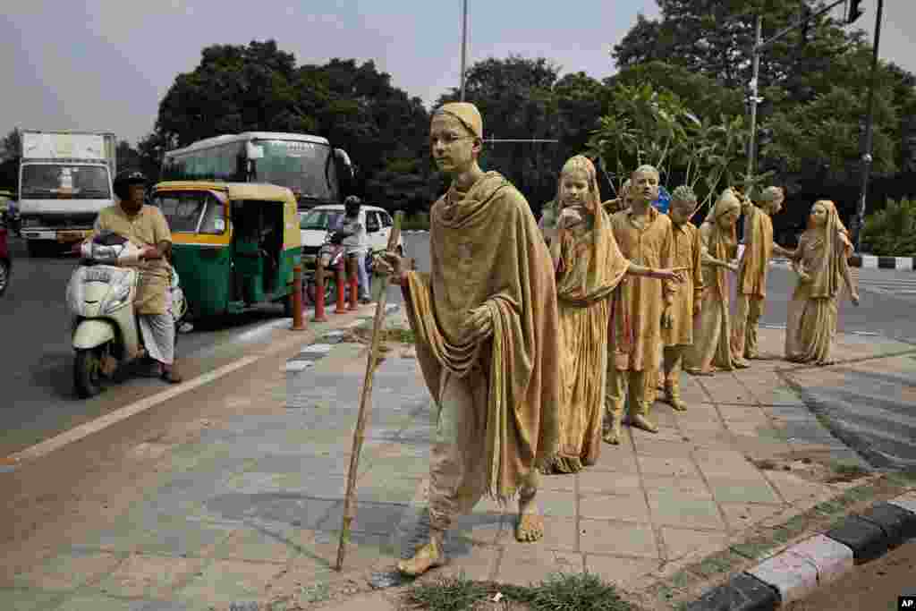 School children dressed up as statues, depicting Indian freedom leader Mahatma Gandhi&#39;s Dandi March, stand at a traffic intersection on the eve of Gandhi&#39;s 150th birth anniversary in New Delhi.