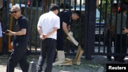 Petugas keamanan memindahkan benda-benda dekat lokasi ledakan di depan kedutaan AS di Beijing, China 26 Juli 2018.