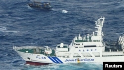 FILE - A Japan Coast Guard vessel sails near a drifting wooden boat carrying men identified as North Koreans off Matsumae town, on Japanese northern island of Hokkaido, in this photo taken by Kyodo, Nov. 29, 2017. 