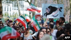 People hold placards and wave Iranian flags during a global protest in solidarity with Iranian women in New York on September 16, 2023, on the first anniversary of the death of Iranian Kurd Mahsa Amini in custody. (Photo by Kena Betancur / AFP)