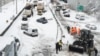 A Greek Army bulldozer plows snow next to abandoned vehicles following heavy snowfall, in Athens, Greece, Jan. 25, 2022.