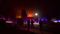 People watch as the Bobcat Fire burns on hillsides behind homes in Arcadia, California on September 13, 2020 prompting mandatory evacuations for residents of several communitu - California wildfires have shrouded much of the western United States in…
