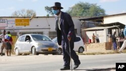 FILE - An elderly man, wearing a mask to protect against COVID-19, walks at a rural shopping center in Zvimba, Zimbabwe, June 25, 2021. 