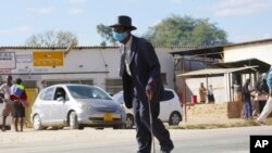 FILE - An elderly man, wearing a mask to protect against COVID-19, walks at a rural shopping center in Zvimba, Zimbabwe, June 25, 2021. 