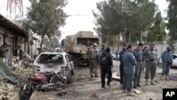 Afghan policemen investigate the scene of a deadly attack in Lashkar Gah, Helmand province on January 26, 2012. A suicide car bomber targeted a NATO convoy of armored vehicles, killing four people and wounding dozens of others.