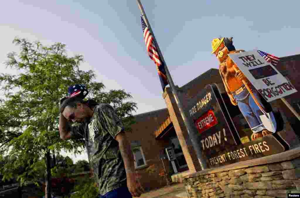 Retired firefighter Roger (did not provide his last name), reacts after placing a sign (R) outside Fire Station No. 1 in Prescott, Arizona June 30, 2013.