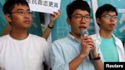 Newly elected lawmaker Nathan Law (C), student leaders Joshua Wong (R) and Alex Chow meet journalists outside a court before a hearing.