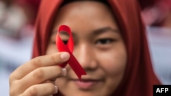 Seorang pelajar menunjukkan pita merah saat kampanye Hari AIDS Sedunia di Medan, Sumatra Utara, 2 Desember 2018. (Foto: AFP)