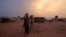 FILE - Sudanese people who fled the conflict in Sudan's Darfur region, carry their jerrycans of water as they walk toward their makeshift shelters in Adre, Chad July 21, 2023.