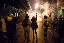 FILE - Protesters hold flowers as tear gas fired by police rises at a demonstration in front of Amir Kabir University in Tehran, Iran, Jan. 11, 2020, to remember victims of a Ukrainian airplane shot down by an Iranian missile.