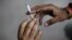 FILE - A man passes a cigarette to another as they sit on a pavement along a road in New Delhi, India, Aug. 18, 2015. 