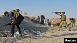 Iraqi security forces fire their weapons during clashes with Islamic State militants on the outskirts of Ramadi, June 15, 2015.