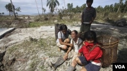 Seorang ibu menangisi suaminya yang meninggal akibat tsunami, didampingi dua anak perempuannya di Pulau Pagai, Mentawai.