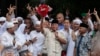 Calon presiden Prabowo Subianto (tengah) mengacungkan karangan bunga dari seorang suporter di Jakarta, 19 April 2019. (Foto: AP)