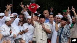 Calon presiden Prabowo Subianto (tengah) mengacungkan karangan bunga dari seorang suporter di Jakarta, 19 April 2019. (Foto: AP)