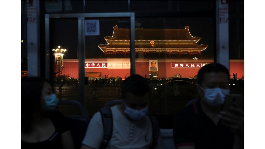 People wearing face masks, following the coronavirus disease outbreak, ride a bus past a portrait of late Chinese chairman Mao Zedong on Tiananmen Gate, in Beijing on June 3, 2020.