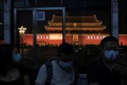 People wearing face masks, following the coronavirus disease outbreak, ride a bus past a portrait of late Chinese chairman Mao Zedong on Tiananmen Gate, in Beijing on June 3, 2020.