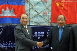 Chinese Ambassador to Cambodia Pan Guang Xue, left, shakes hands with Cambodian first vice president of the National Committee for Disaster Management Nhim Vanda at Phnom Penh international airport, Oct. 15, 2011.