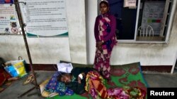 The wife of a tea plantation worker, who consumed bootleg liquor, stands next to her husband as he is being treated in a corridor of a government-run hospital in Golaghat in the northeastern state of Assam, India, Feb. 23, 2019. 
