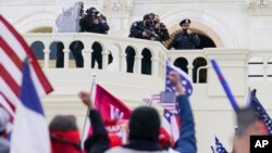 FILE - Supporters loyal to then-President Donald Trump challenge authorities before successfully breaching the Capitol building during a riot on its grounds, Jan. 6, 2021. Rioters tried to overturn America's presidential election, undercutting the nation'