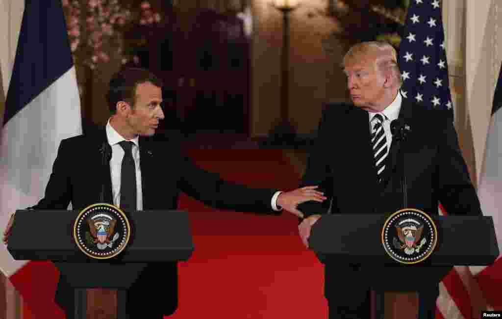 French President Emmanuel Macron reaches out to U.S. President Donald Trump as he speaks during their joint news conference at the White House in Washington, April 24, 2018.