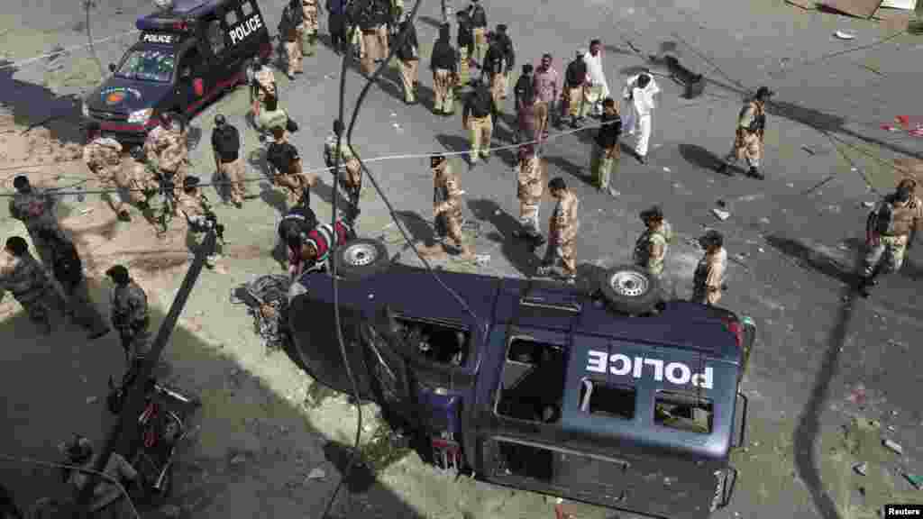 Paramilitary soldiers and police officers gather at the site of a bomb blast in Karachi, June 26, 2013.