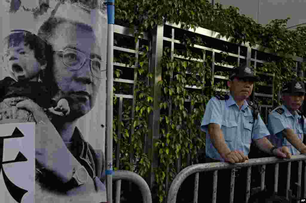 香港中联办外面，警察站岗，旁边是示威者带来的刘霞拍摄的刘晓波照片（2017年7月10日）