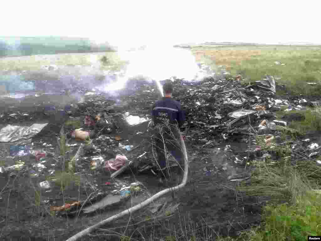 Um bombeiro tenta apagar as chamas do avião que caiu na Ucrânia esta Quinta-feira, 17 de Julho 2014