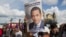 A man holds up a campaign poster of Guatemala's President Jimmy Morales during a gathering to show support for the Commissioner of the United Nations International Commission Against Impunity, Ivan Velasquez in Guatemala City, Saturday, Aug. 26, 2017. 
