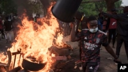 A demonstrator walks past a barricade set on fire during a protest in support of main opposition leader Ousmane Sonko in Dakar, Senegal, May 29, 2023. 