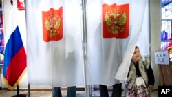 A child looks out from a voting booth at a polling station during parliamentary elections in the Russian embassy in Vilnius, Lithuania, Sept. 18, 2016.