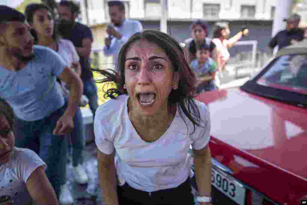 A Syrian woman screams for help for her husband who was injured by stone throwing by members of the Lebanese Forces group, who attacked buses carrying Syrians traveling to vote in the town of Zouk Mosbeh, north of Beirut, Lebanon.