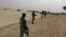In this Sept. 16, 2012 photo, members of Islamist group Ansar Dine stand guard as they prepare to amputate the hand of a young man found guilty of stealing rice in Timbuktu, Mali. 