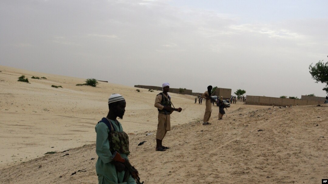 In this Sunday, Sept. 16, 2012 photo, members of Islamist group Ansar Dine stand guard around the area where they are preparing to amputate the hand of a young man found guilty of stealing rice, in Timbuktu, Mali. In a report launched Thursday, Sept. 20, 2012, Amnesty International says it has documented 'horrific abuses' against civilians in Islamist-controlled northern Mali, including the recruitment of child soldiers, sexual violence, extra-judicial executions, and seven amputations just since August. (AP Photo)