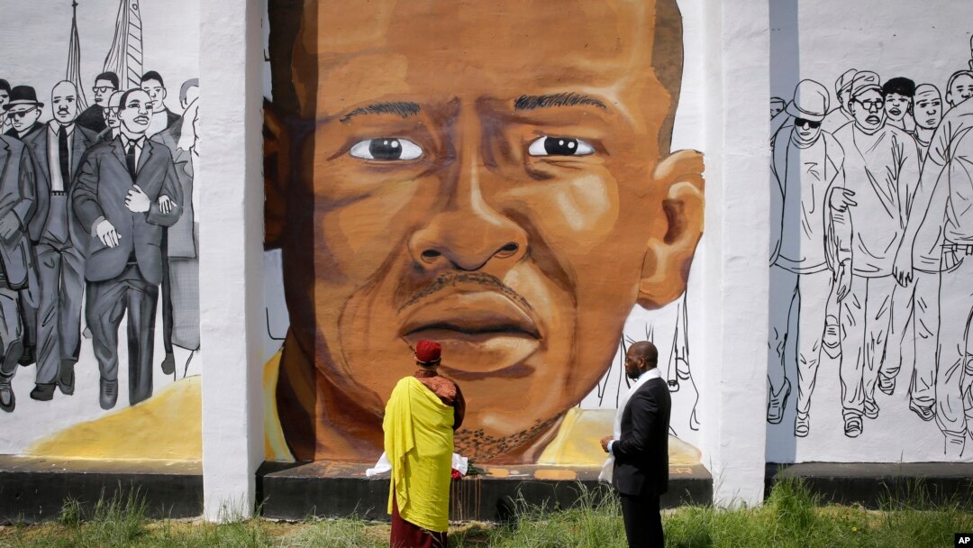 FILE - The Gyalwang Drukpa, bottom center, the Buddhist leader of South Asia, prays in front of a mural depicting Freddie Gray alongside the Rev. Jamal Bryant during a walking tour with other faith and community leaders, Thursday, May 7, 2015.