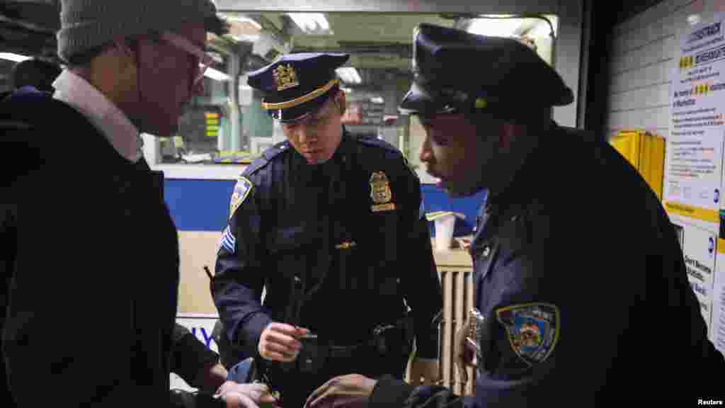 New York Police Department officers investigate a commuter's bag in the Times Square subway station in New York during an increase in security following fatal explosions in Boston, April 15, 2013.