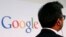 一位男士站在谷歌的标牌前方。（2013年11月4日）
