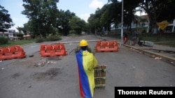 Un manifestante de primera línea envuelto en una bandera colombiana posa para una foto en una barricada en Cali.