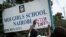 An activist puts a message on the sign board at the main entrance of Moi Girls School Nairobi, a prestigious government boarding school in Nairobi, Kenya, June 4, 2018, during a protest against alleged rape of three girls at the school.